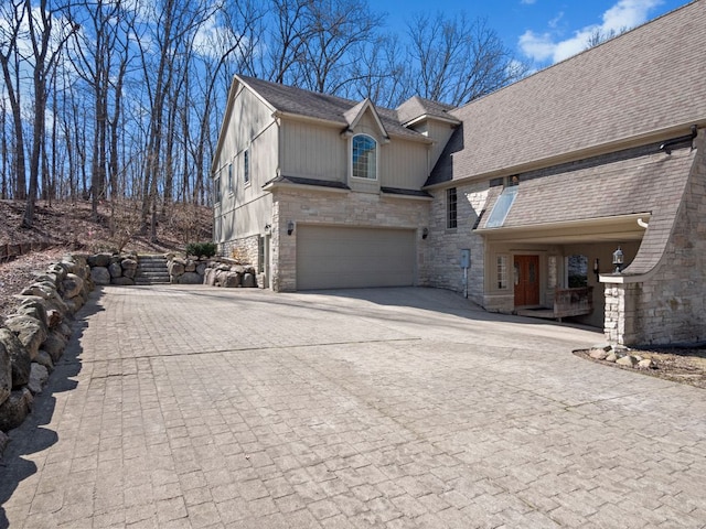 6705 College Park, Clarkston, MI 48346 - view of side of home featuring decorative driveway, a shingled roof, stone siding, and a garage