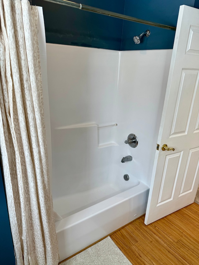 bathroom with hardwood / wood-style flooring and shower / bath combo with shower curtain