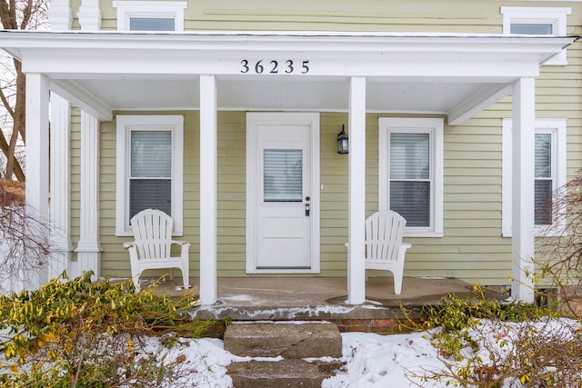 snow covered property entrance featuring covered porch