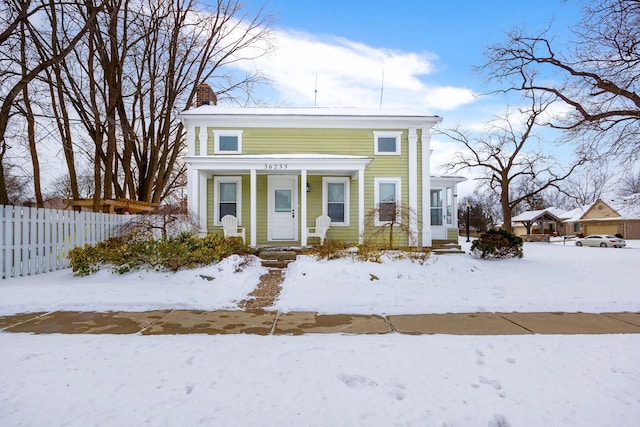 view of front of home with covered porch, a chimney, and fence