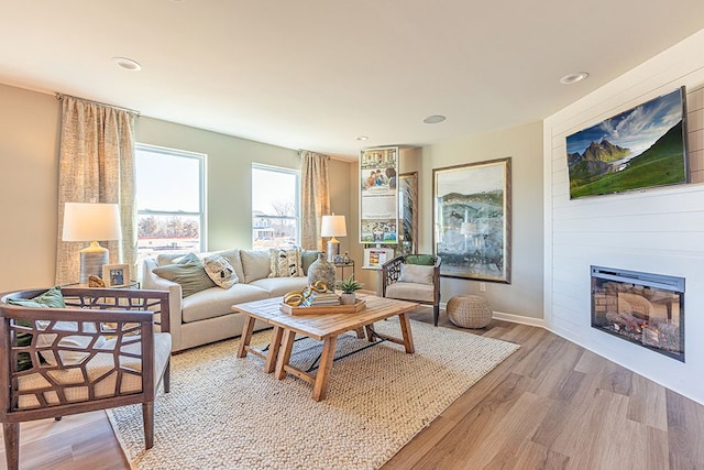 living room with recessed lighting, light wood-type flooring, and a large fireplace