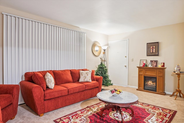 living room with light carpet, a glass covered fireplace, and baseboards