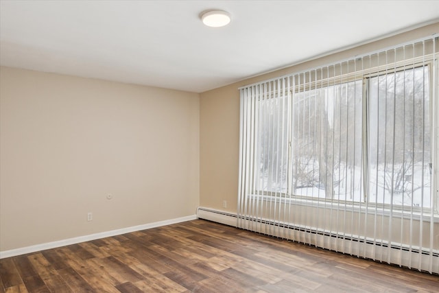 empty room with a baseboard heating unit, dark wood-type flooring, and baseboards