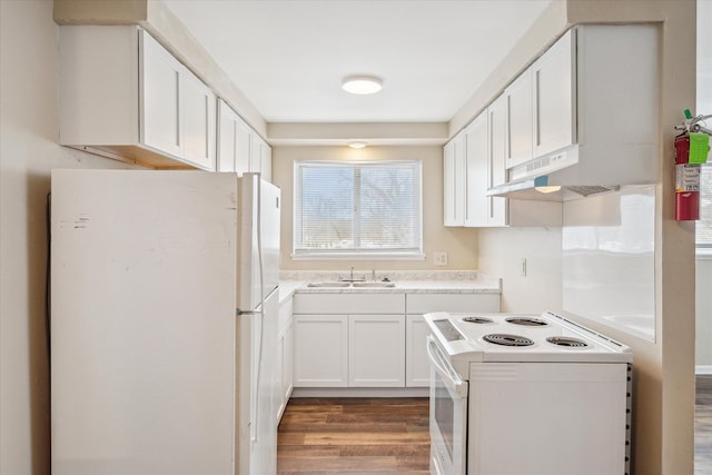 kitchen featuring white appliances, white cabinets, light countertops, under cabinet range hood, and a sink