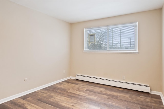 unfurnished room with a baseboard heating unit, baseboards, and wood finished floors