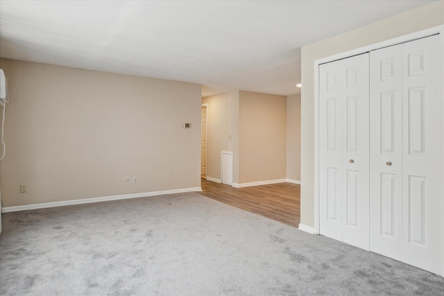 unfurnished bedroom featuring baseboards, a closet, and light colored carpet