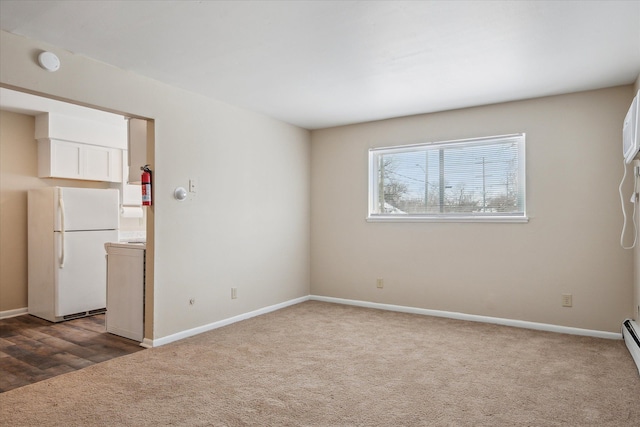 empty room with dark colored carpet, baseboards, and a baseboard radiator