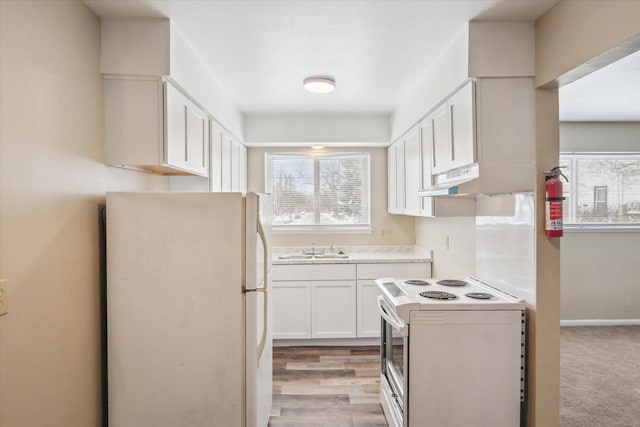 kitchen featuring white appliances, light wood finished floors, light countertops, white cabinetry, and a sink