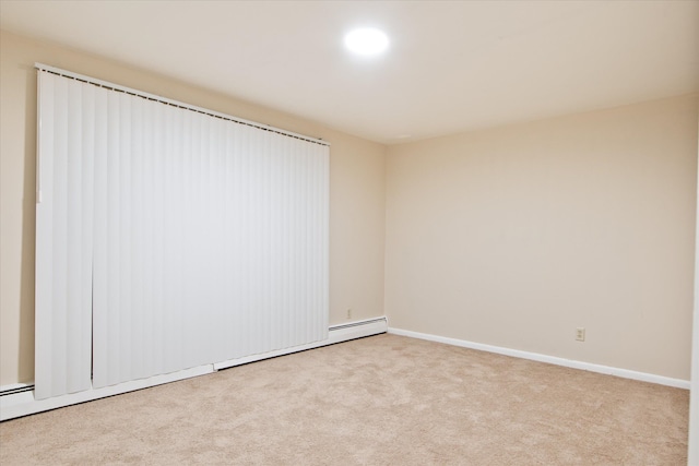 spare room with baseboards, a baseboard heating unit, and light colored carpet