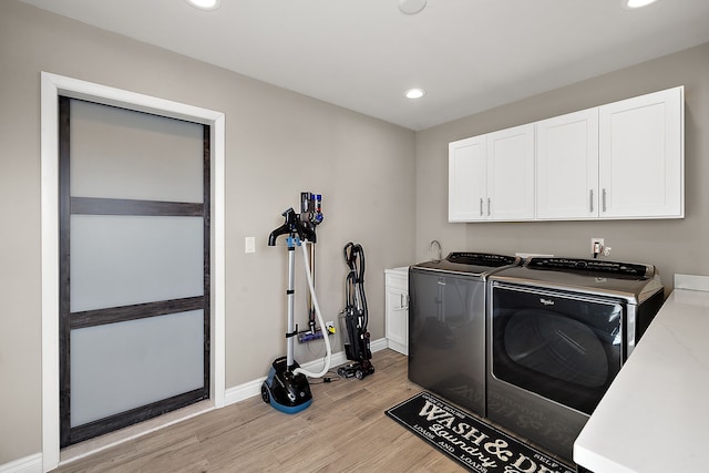 clothes washing area with cabinets, washer and dryer, and light hardwood / wood-style floors