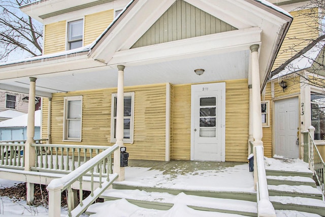 snow covered property entrance featuring covered porch