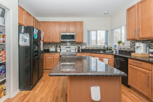 kitchen featuring sink, a kitchen island, dark stone countertops, and black appliances