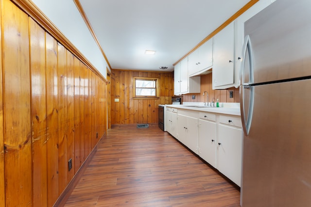 kitchen featuring a sink, white cabinets, light countertops, freestanding refrigerator, and electric range oven