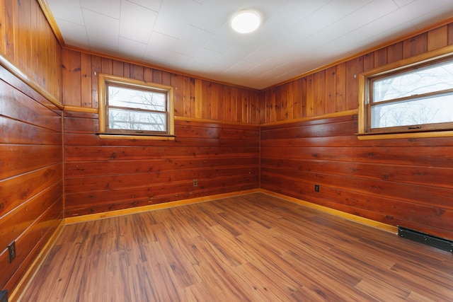 empty room with a sauna, wooden walls, visible vents, and wood finished floors