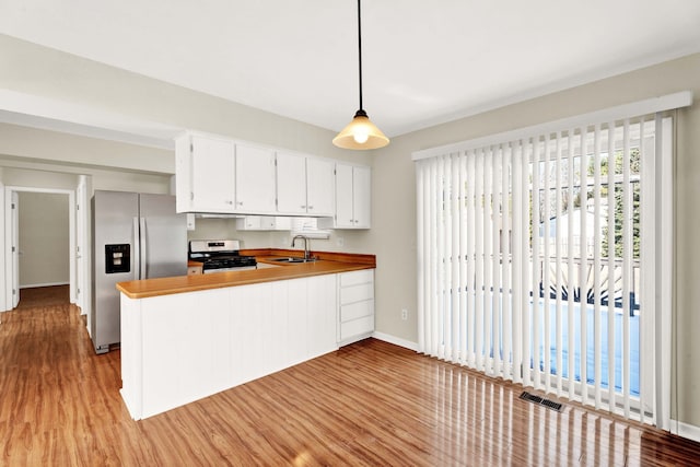 kitchen featuring appliances with stainless steel finishes, light wood-type flooring, pendant lighting, sink, and white cabinetry