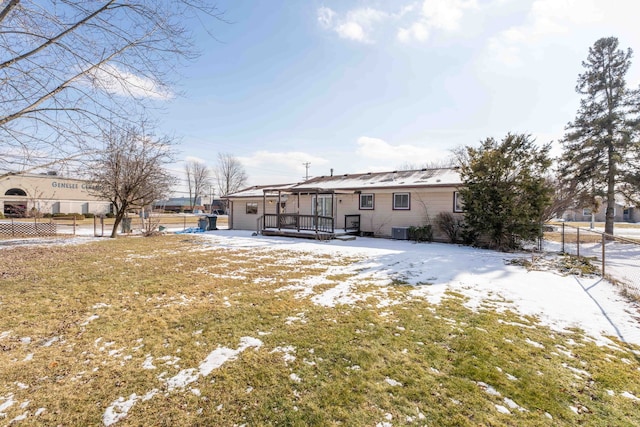 snow covered property with central AC and a yard