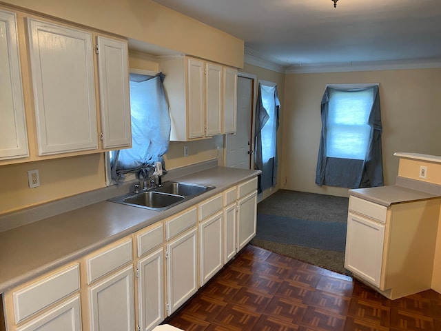 kitchen with crown molding, white cabinetry, sink, and dark parquet floors