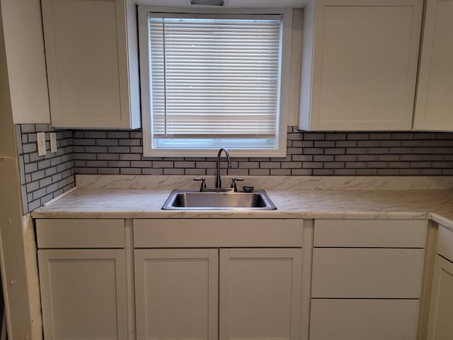 kitchen featuring white cabinetry, sink, decorative backsplash, and light stone counters