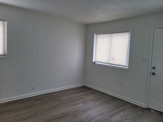 unfurnished room with dark hardwood / wood-style flooring and a textured ceiling