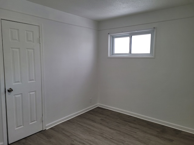 unfurnished room with dark wood-type flooring and a textured ceiling