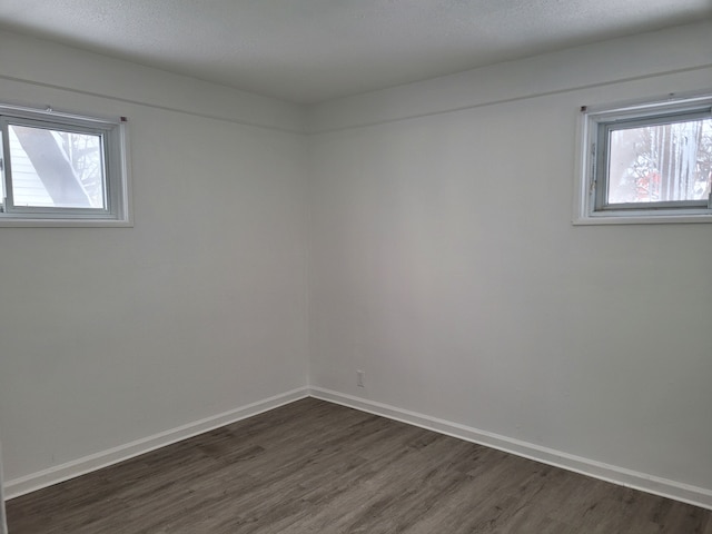 spare room featuring dark hardwood / wood-style flooring and a textured ceiling