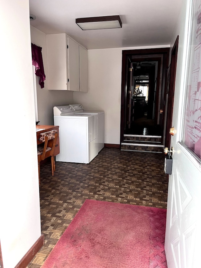 laundry room with dark floors, cabinet space, washer and clothes dryer, and baseboards