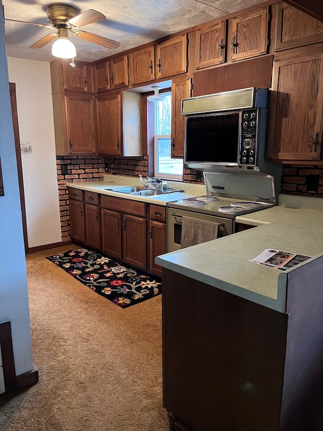 kitchen with ceiling fan, electric range, a sink, light countertops, and brown cabinets