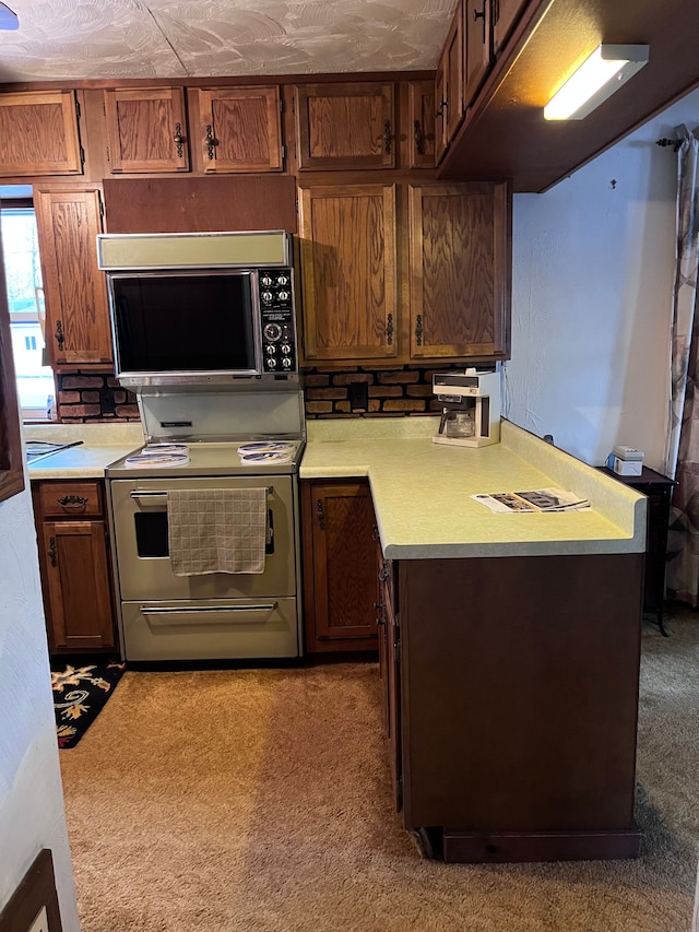 kitchen featuring light countertops, electric range, light carpet, black microwave, and a peninsula