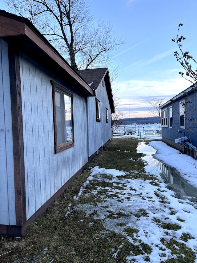 view of snow covered exterior with a shingled roof