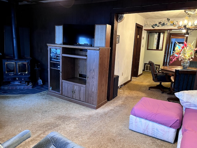 carpeted living area featuring a wood stove and a chandelier