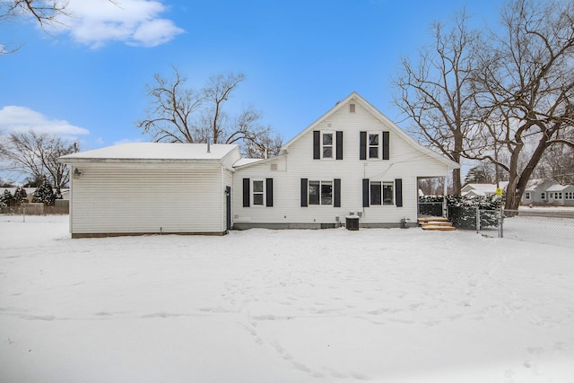 snow covered rear of property featuring central AC unit