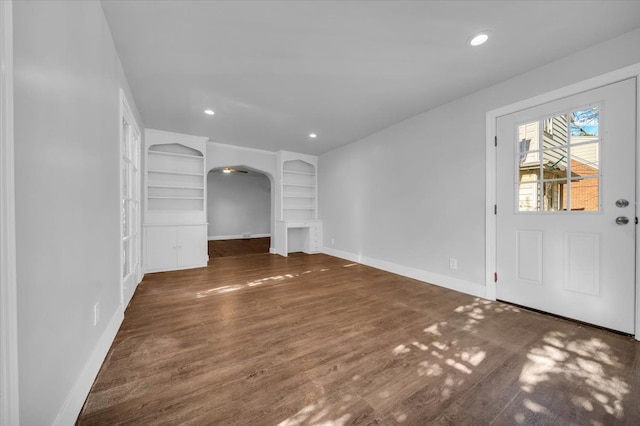 unfurnished living room with dark wood-type flooring and built in features