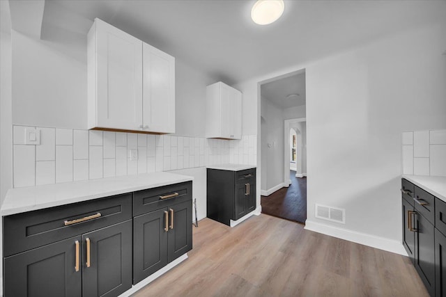 kitchen featuring white cabinetry, light hardwood / wood-style floors, and tasteful backsplash