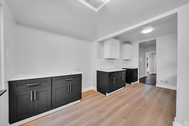 kitchen featuring white cabinets, backsplash, and light hardwood / wood-style flooring