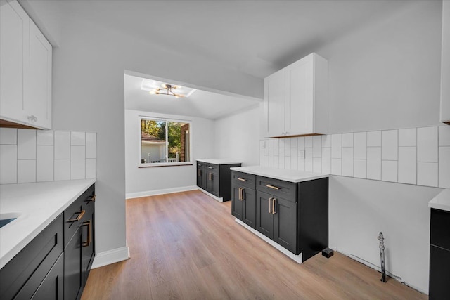 kitchen with white cabinetry, decorative backsplash, and light wood-type flooring