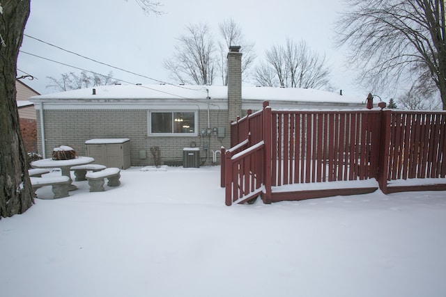 snowy yard featuring a garage and cooling unit