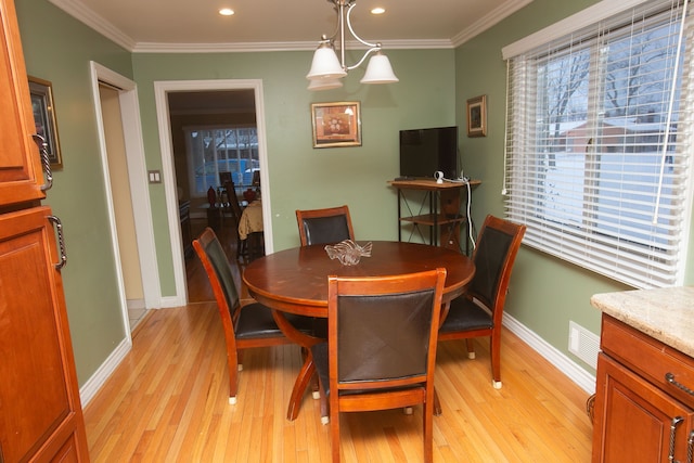 dining space with visible vents, ornamental molding, light wood-style flooring, and baseboards