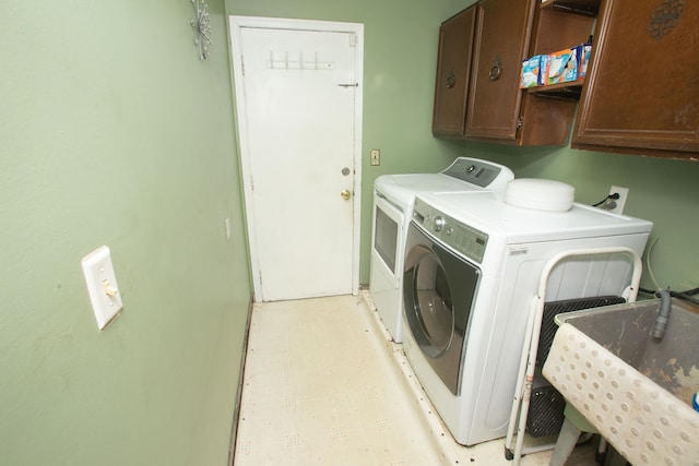 clothes washing area featuring a sink, cabinet space, washer and clothes dryer, and light floors