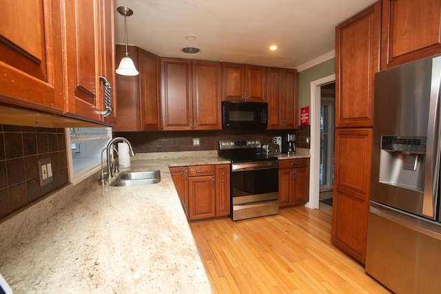 kitchen featuring hanging light fixtures, backsplash, appliances with stainless steel finishes, light wood-style floors, and a sink