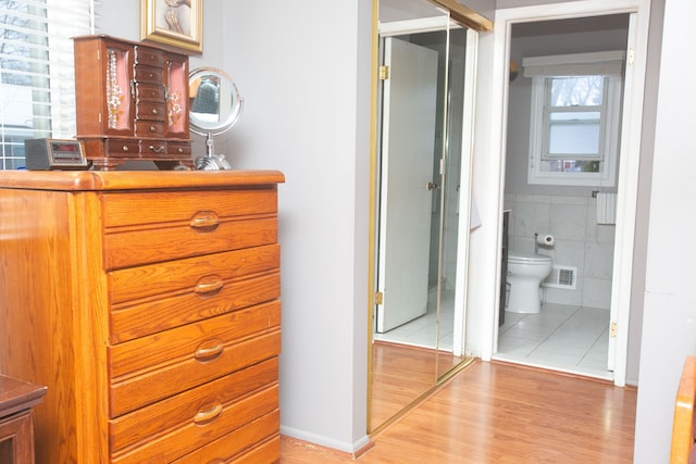 bathroom featuring toilet, wood finished floors, visible vents, and tile walls