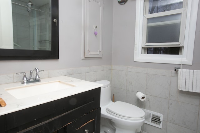 full bathroom featuring visible vents, toilet, an enclosed shower, vanity, and tile walls