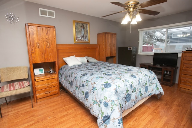 bedroom featuring a ceiling fan, visible vents, and light wood-style flooring