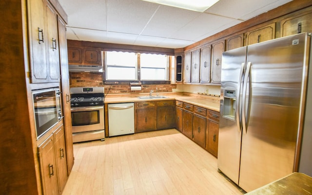 kitchen with a drop ceiling, sink, stainless steel appliances, and light wood-type flooring