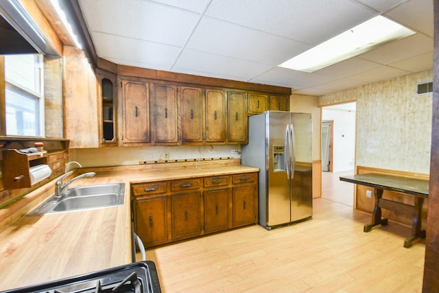 kitchen featuring sink, a paneled ceiling, light hardwood / wood-style floors, and stainless steel fridge with ice dispenser