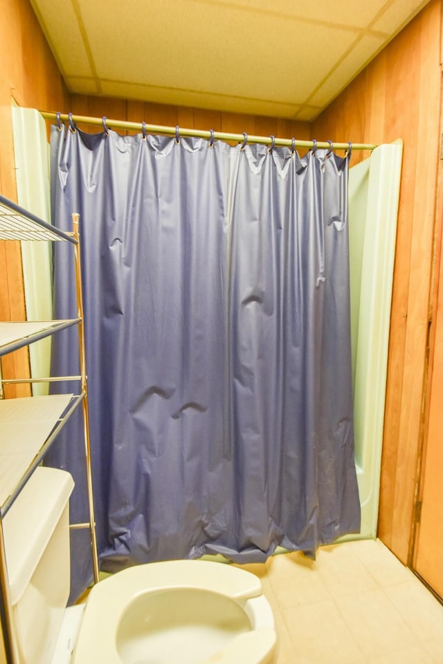 bathroom with a paneled ceiling, toilet, and walk in shower