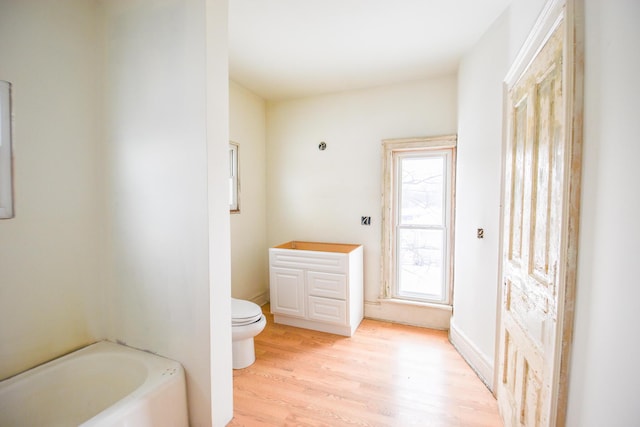 bathroom with toilet, hardwood / wood-style floors, and a tub