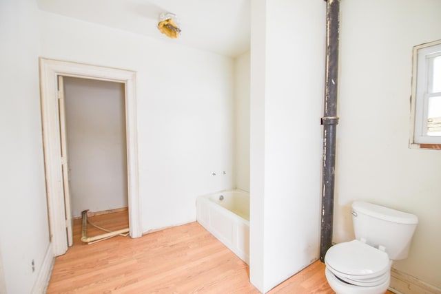 bathroom with a bathtub, wood-type flooring, and toilet