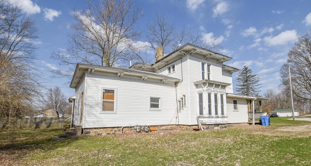 back of house featuring a chimney, fence, a yard, and entry steps