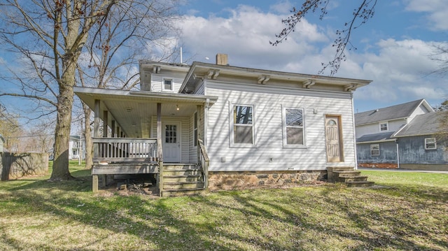 back of house featuring a chimney, entry steps, and a yard