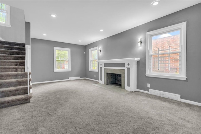 unfurnished living room featuring carpet flooring and a high end fireplace